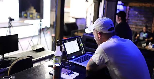 Person working on a laptop backstage with a music event software