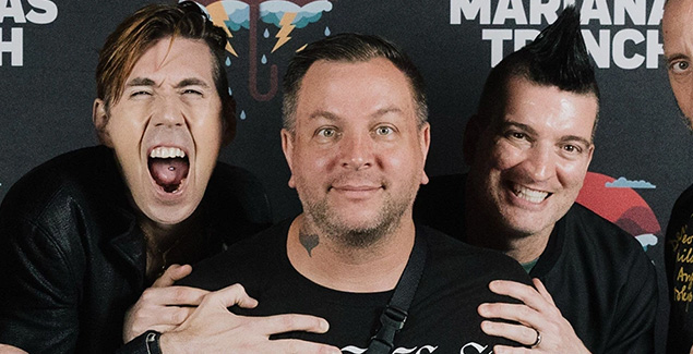 Three men posing together, smiling.